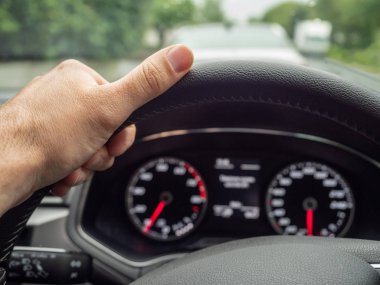 Şehirde araba sürerken sol eliyle direksiyonu tutan sürücü. Seçici odaklama.