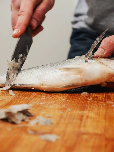 Fishmonger werkt aan ontkalkings zeebrasem op een houten plank, selectieve focus. — Stockfoto