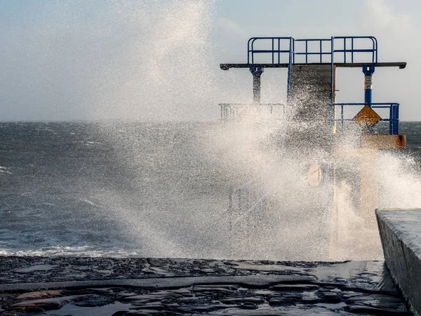 Black Rock diving rock at storm and high tide covered by a giant splash of water. Salthill, Galway city, Ireland.
