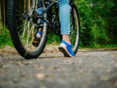 Arka planda odak koyu forrest. Bulanık kız genç ayak ve bisiklet ormana giden bir yolda. Risk, macera, korkutucu bilinmeyen değerlendirme kavramı.