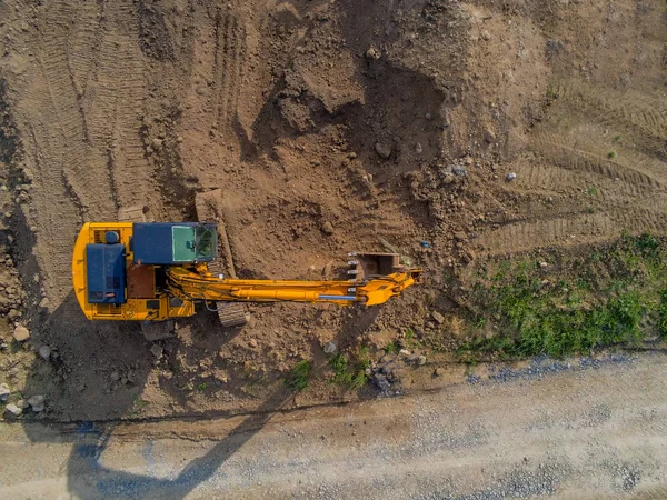 Vista aérea superior em uma escavadeira de canteiro de obras trabalhando no local. Cerca de segurança e árvores verde.Escavadeira trabalhando, canteiro de obras, vista aérea superior. Escavando no solo . — Fotografia de Stock