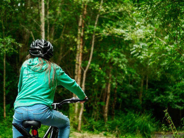 Mladá teenagerka s dlouhými vlasy na kole a dívá se do temného lesa. Koncept venkovní aktivity, sport, Cyklistika, kopírování prostoru. Stock Fotografie