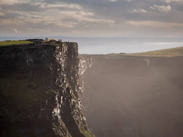 Turister som går på toppen av Cliff of Moher, Irland, är berg strukturen synlig. Koncept resor i Europa, Irish Landmark. — Stockfoto