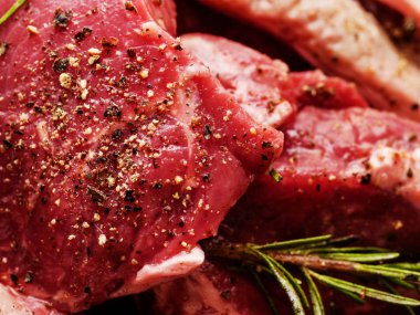 Zeytinyağı, otlar, biberiye ile marine edilmemiş pişmemiş biftekler. Yakın çekim.