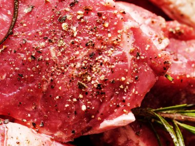 Zeytinyağı, otlar, biberiye ile marine edilmemiş pişmemiş biftekler. Yakın çekim.