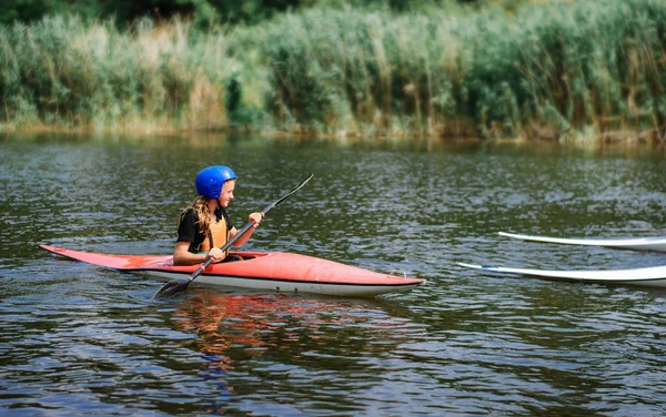 Młody nastolatek dziewczyna aktywnie zarządza łodzi kajak sportowy na piękną rzeką — Zdjęcie stockowe