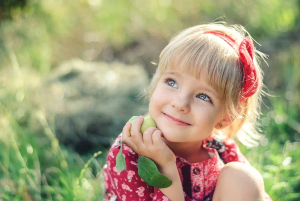 Cute Little girl with a Apple in Her Hand Outdoors. Royalty Free Stock Photos