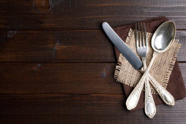Rustic cutlery on sackcloth on wooden table