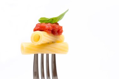 Beyaz arka plan makarna. Rigatoni, domates ve fesleğen çatal üzerinde. İtalyan mutfağı concep