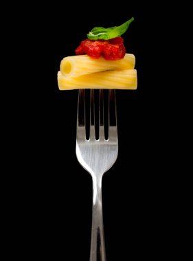 Makarna siyah arka plan. Rigatoni, domates ve fesleğen çatal üzerinde. İtalyan mutfağı concep