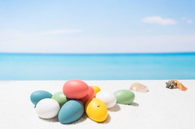 Tropikal plaj arka plan üstünde Paskalya yortusu. Yumurta beyaz kum üzerinde. Tatil ve seyahat kavramı