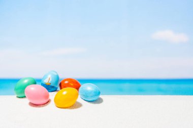 Tropikal plaj arka plan üstünde Paskalya yortusu. Yumurta beyaz kum üzerinde. Bahar tatil ve seyahat kavramında