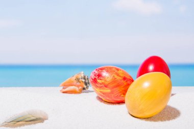 Tropikal plaj arka plan üstünde Paskalya yortusu. Yumurta beyaz kum üzerinde. VAC