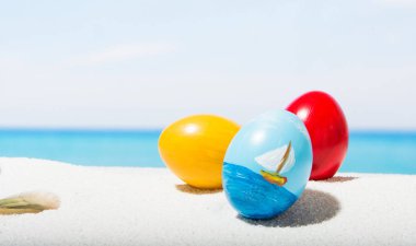 Tropikal plaj arka plan üstünde Paskalya yortusu. Yumurta beyaz kum üzerinde. VAC