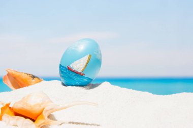 Tropikal plaj arka plan üstünde Paskalya yortusu. Yumurta beyaz kum üzerinde. VAC