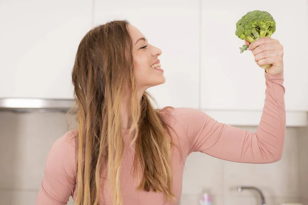 Attractive woman holding fresh raw broccoli