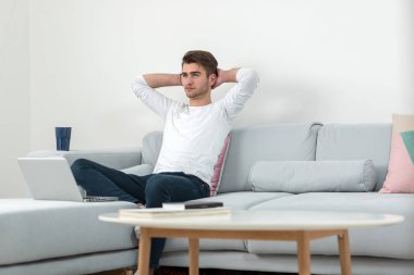 Yakışıklı genç gülümseyen işadamı ile bir dizüstü bilgisayar evden çalışma