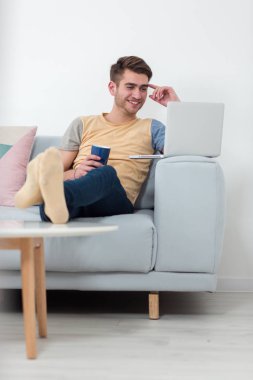 Adam çalışma üzerinden ana sayfa kullanarak dizüstü bilgisayarda kanepe oturma odasında