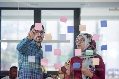 İş adamları ofiste buluşup, fikirlerini paylaşmak için not tutuyorlar. Beyin fırtınası konsepti. Cam duvara yapışkan bir not..