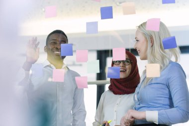 İş adamları ofiste buluşup, fikirlerini paylaşmak için not tutuyorlar. Beyin fırtınası konsepti. Cam duvara yapışkan bir not..