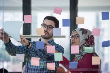 İş adamları ofiste buluşup, fikirlerini paylaşmak için not tutuyorlar. Beyin fırtınası konsepti. Cam duvara yapışkan bir not..