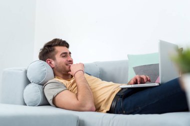 teknoloji, ev ve yaşam kavramı - laptop ile evde çalışan adam gülümsüyor