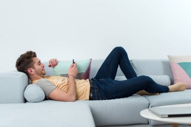 Modern kullanıcı. Koltukta oturan ve cep telefonu kullanırken dinlenme yakışıklı adam çok iyi konsantre