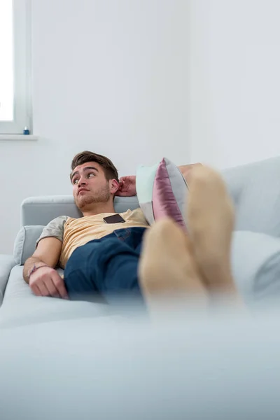 Relaxed man resting lying on a couch in living room