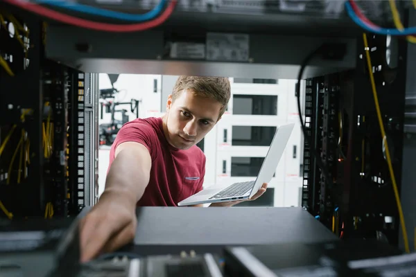 サーバー キャビネット データ センターのスーパー コンピューターでの作業中にワイヤを接続する若い男 — ストック写真