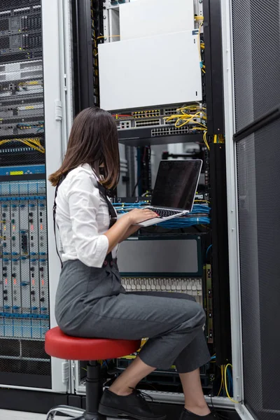 Technician apecialist woman using laptop while analyzing server in server room