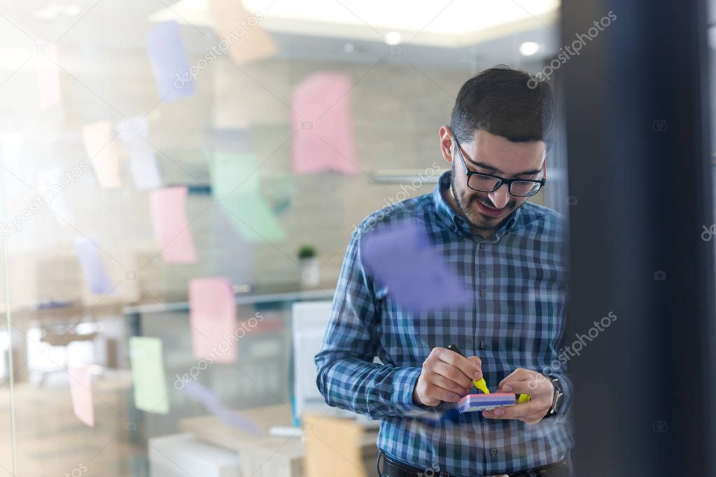 Businessman sticking notes to share idea. Brainstorming concept. Sticky notes on glass wall.