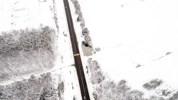 road between forests and fields during the winter from the air