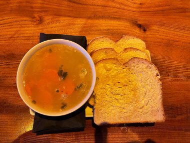 Üç dilim kızarmış ekmek ve tereyağlı sıcak sebze çorbası. 