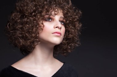 Doğal makyaj ve afro bukleler ile güzel bir genç kız portresi. Siyah bir arka plan üzerinde.