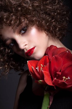 Parlak makyaj ile güzel bir genç kız portresi. Afro bukleler ve kırmızı ruj ve yüzünde kırmızı bir çiçek. Siyah bir arka plan üzerinde.