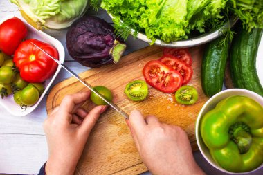 Eller bir aşçı kesim domates taze sebze salatası yapmak için. Lezzetli sağlıklı gıda ürünleri kümesi: yeşil ve kiraz domates, salatalık, tatlı biber, lahana ve marul salatası.