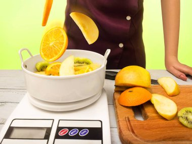 Atma bir aşçı kadın terazi tartı üzerinde meyve dilimlenmiş. Sağlıklı yaşam ve yemek, pişirme ve kavram Diyet.