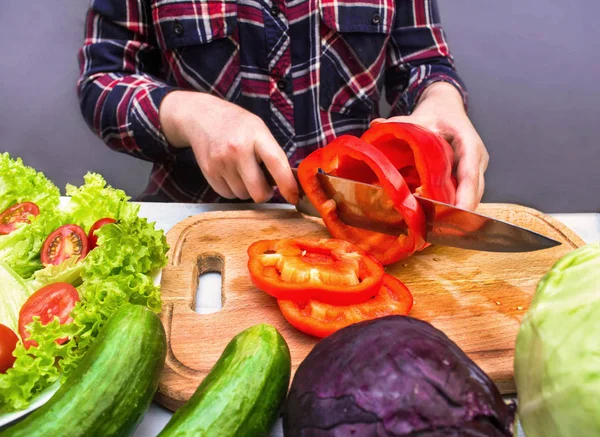 Kırmızı tatlı biber taze sebze salatası yapmak için kesme bir genç ev hanımı kadın. Lezzetli sağlıklı gıda ürünleri kümesi: domates, salatalık, tatlı biber, lahana ve marul salatası.
