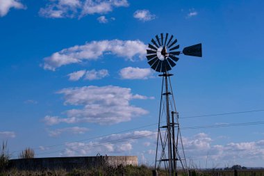 Yel değirmeni ve su birikintisi, mavi gökyüzünün altında