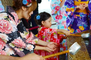 Tokyo, Japonya - 28 Mayıs 2018: Sensoji Budist tapınağını girmeden önce bir tören arıtma ritüel bir parçası olarak Japon kimono içme suyu bir Chozuya giyen Japon familyl. 