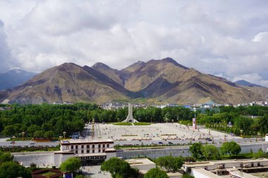 Potala Sarayı ve Sarayı önünde Lhasa şehrinin panoramik kare, modern bina ve dağlar, çok uzak bir Tibet barışçıl kurtuluş Anıtı ve mavi gökyüzü