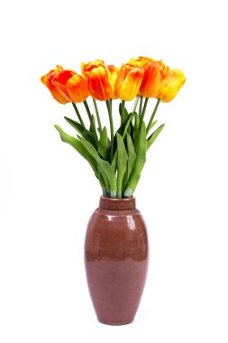 Vazoda beyaz bir zemin üzerinde turuncu-kırmızı laleler.