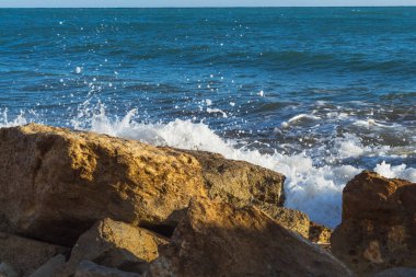  Kıbrıs kıyı şeridinin deniz kenarındaki kayalara çarpan dalgalarla manzarası, doğal ışık altında dinamik sıçramalar ve deniz spreyi yaratarak Akdeniz kıyısının saf güzelliğini gözler önüne seriyor.