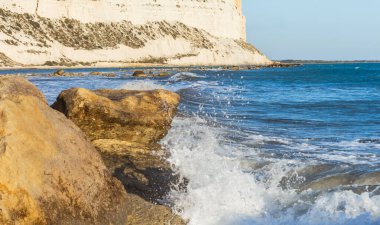  Kıbrıs kıyı şeridinin deniz kenarındaki kayalara çarpan dalgalarla manzarası, doğal ışık altında dinamik sıçramalar ve deniz spreyi yaratarak Akdeniz kıyısının saf güzelliğini gözler önüne seriyor.
