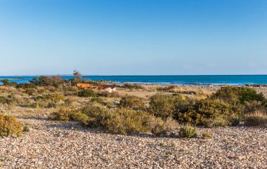  Scenic view of a deserted old boat resting on the sandy shore of a Cyprus beach, with calm sea and clear horizon under a sunny sky, evoking a sense of nostalgia and coastal tranquility