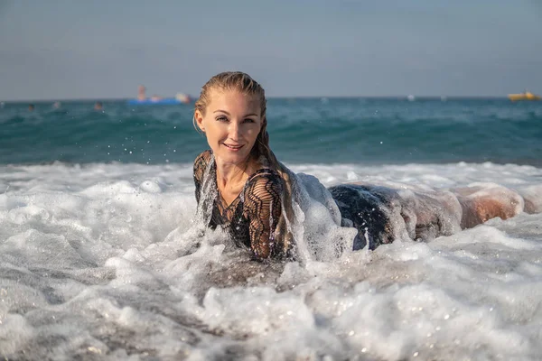 Uma mulher pouco impressionante está na praia, a sombrear nuvens. Ondas são soberbas para ela — Fotografia de Stock