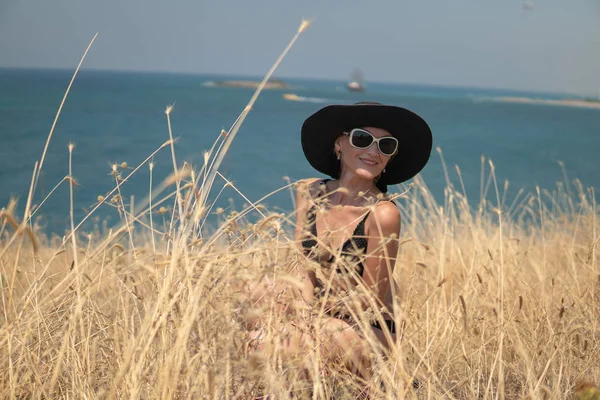Una giovane signora seduta in un campo sulle rive dell'oceano o del mare e godersi il tramonto — Foto Stock
