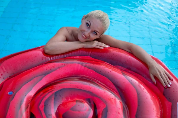 Hermosa mujer nada en un colchón de aire en el estanque de un hermoso hotel —  Fotos de Stock