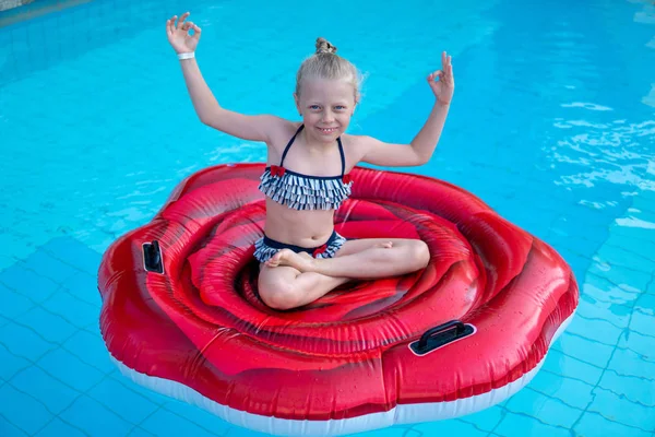 Bebé encantador sentado en un colchón inflable y nada en la piscina al aire libre en las vacaciones de verano —  Fotos de Stock