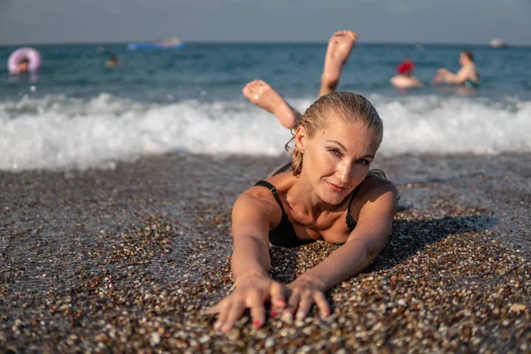 La bella donna posa su di me salvare l'oceano e ascolta liscio a un'ondata di onde, è affascinato nel pomeriggio, sul sole — Foto Stock